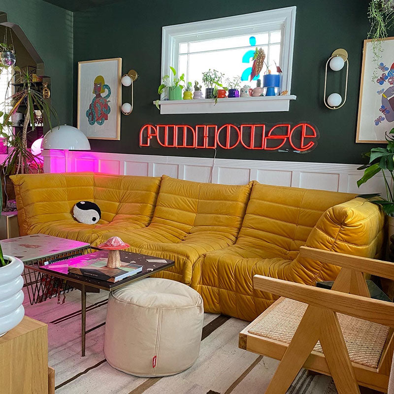 Maximalist living room with dark green walls and a gold orange couch.